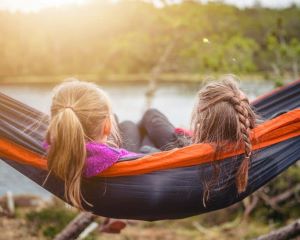 Girls sitting on blue hammock at sunset