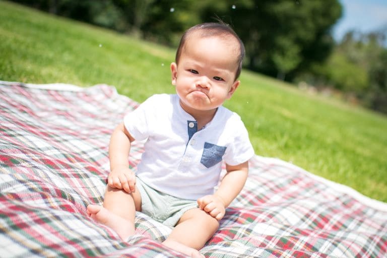 Child on checkered picnic blanket in grass