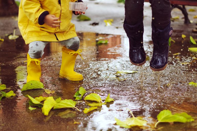 Kids jumping in a puddle with rain boots