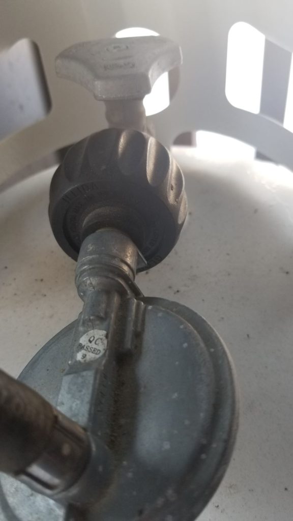 A close up of the grill to propane tank connection. Propane tank valve.