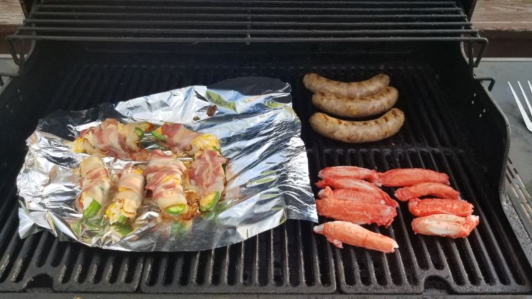 Campfire cooking jalapeno poppers on the grill, sausage and crab legs.