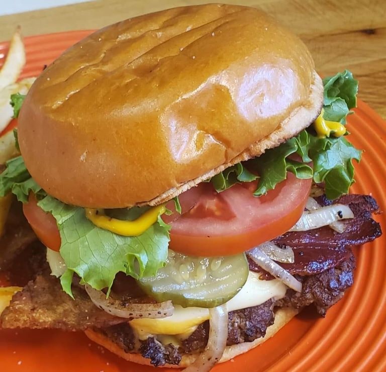 Smash burger with tomato, pickle, onion, bacon, lettuce.