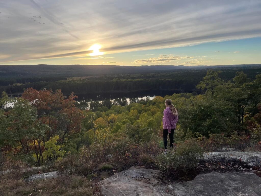 A girl on a rock cliff with the sun rising